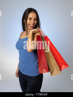 Happy latin young woman holding colorful bags happy and cheerful after a shopping day. Excited teenager with paper bags buying in new season sales. In Stock Photo