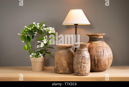 Decorative living room still life with lamp, flowering plant and old cute wooden jugs. Home interior concept. Stock Photo