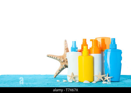 Different sunscreen sprays with starfishes and seashells on color table isolated on white background. Safe tan Stock Photo