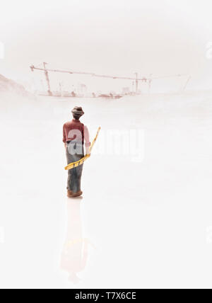 View of miniature toy worker standing with construction site background. Vintage style. Focus on worker. Stock Photo