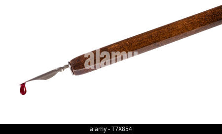 side view of red ink drop dripping from nib of brown dip pen close up isolated on white background Stock Photo