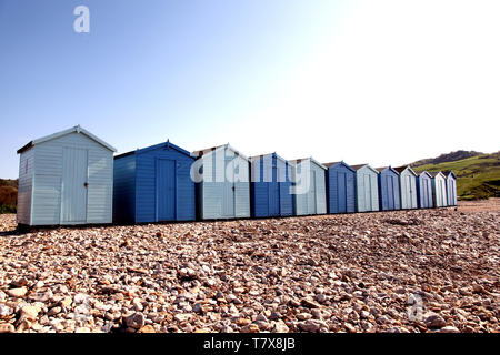 Charmouth Beach, Dorset, UK - Wooden beach Huts on pebble beach at Charmouth with blue sky in background with copy space Stock Photo