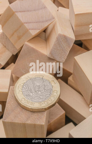 New pound coins + jumbled / tumbled wooden bricks & blocks. Sterling pound crash, pound sell-off interest rate collapse, market crash, bank collapse Stock Photo