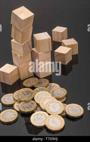New pound coins + jumbled / tumbled wooden bricks & blocks. Sterling depreciation, drop in value of £, Pound crashes, pound sell-off interest rate cut Stock Photo