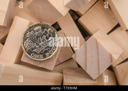 New pound coins + jumbled / tumbled wooden bricks & blocks. Sterling pound crash, pound sell-off interest rate collapse, market crash, bank collapse Stock Photo