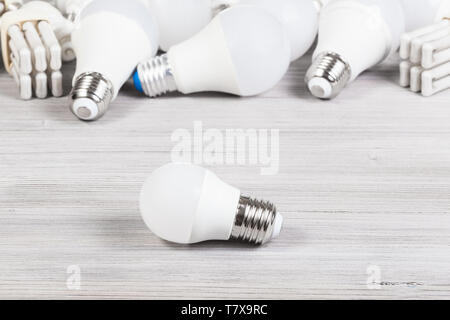 white LED bulb light and several energy-saving lamps on gray wooden board Stock Photo