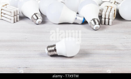 one white LED bulb light and energy-saving lamps on gray wooden board Stock Photo