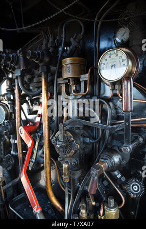 On the footplate of a British, vintage steam locomotive: portrait close up of the working controls and levers inside engine driver's cab. Stock Photo