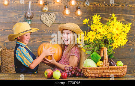 Siblings having fun. Family farm. Farm market. Children presenting farm harvest wooden background. Kids farmers girl boy vegetables harvest. Farming teaches kids where their food comes from. Stock Photo