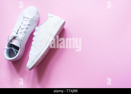 White trendy sneak shoes on pink background for text, discputs and sales. Stylish female sneakers. Stock Photo