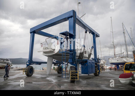 Tivat, Montenegro, April 29th 2019: Sailing yacht transporting in the sea after repair by marina mobile crane. Stock Photo