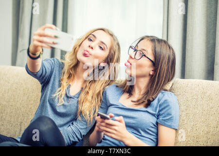 Two teen girls smile and take a selfie together. They make grimaces out of their tongue. Stock Photo