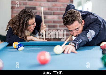 Young modern couple playing pool table billiard game. Stock Photo
