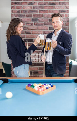 Couple cheering with beer next to billiard pool table. Stock Photo