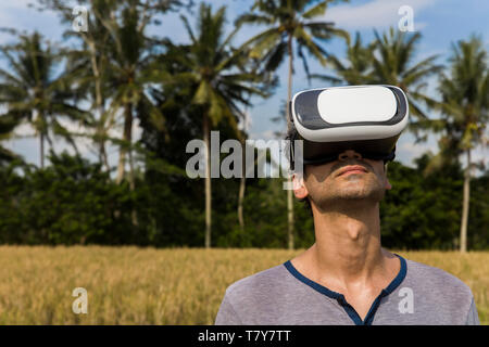 Young man wearing VR glasses in the tropical rice field Stock Photo