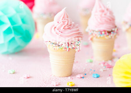 Pink soft serve ice cream with colorful sprinkles in little waffle cups Stock Photo