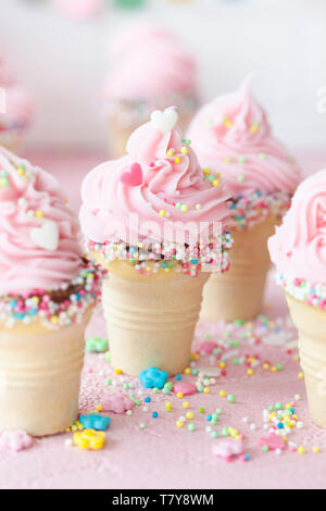 Pink soft serve ice cream with colorful sprinkles in little waffle cups Stock Photo