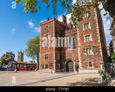 Lambeth Palace London. Morton's Tower with Parliament and red London Bus. Red brick Tudor gatehouse forming the entrance to Lambeth Palace London UK Stock Photo