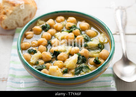 Chickpea soup with spinach and dry salted cod in a rustic bowl. Traditional spanish recipe in the Holy Week. Stock Photo