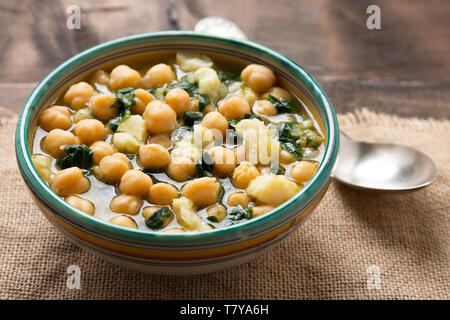 Chickpea soup with spinach and dry salted cod in a rustic bowl. Traditional spanish recipe in the Holy Week. Stock Photo