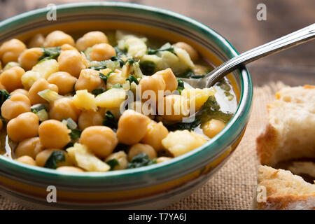 Chickpea soup with spinach and dry salted cod in a rustic bowl. Traditional spanish recipe in the Holy Week. Stock Photo