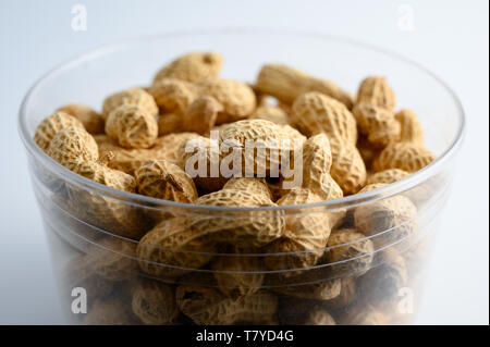 Plastic cup full of peanuts in nutshell on white background Stock Photo
