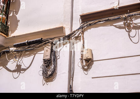 outdoor wall with a few electrical boxes and lots of electrical wires connecting the boxes. Stock Photo