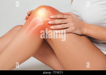 Woman wearing sports clothes suffering from pain in knee. Close-up painful knee with bones Stock Photo
