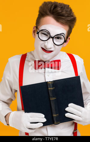 portrait of mime man artist with book ape isolated on yellow background Stock Photo