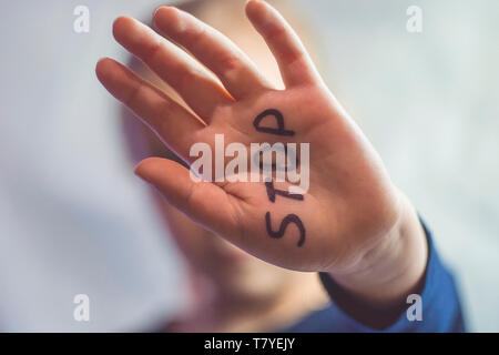 Concept of domestic violence and child abusement. A little girl shows her hand with the word STOP written on it. Children violence. Stock Photo