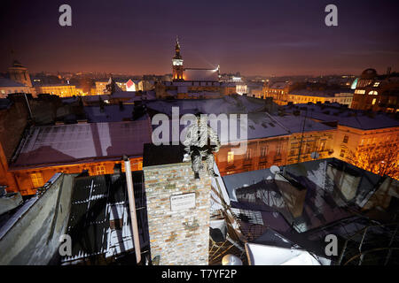 Sculpture a chimney sweep on the roof of the House of Legends, winter night, Lviv, Ukraine. Lvov is the most attractive city for tourists in Ukraine Stock Photo