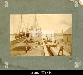 Loading lumber on a ship, ca. 1890.  MP AP Stock Photo