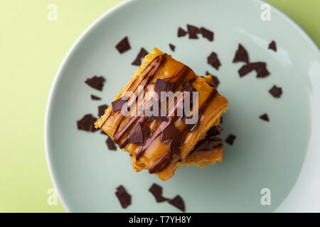 Stack of two sweet potato blondies with thin lines of chocolate and caramel icing running down and chocolate chips on teal plate - top down view Stock Photo
