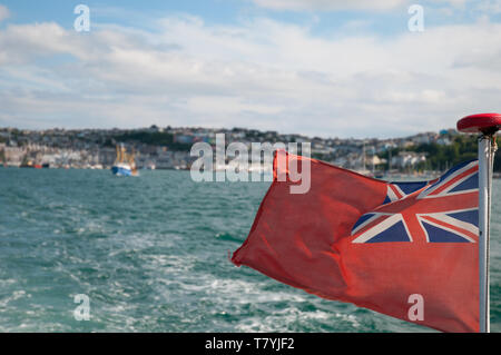 British maritime flag 'Red Ensign' or 'Red Duster' waving in the wind on the back of a motored boat. Stock Photo