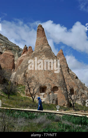 A Muslim woman walks along path through unusual rock formations at outdoor museum in Cappadocia, Turkey