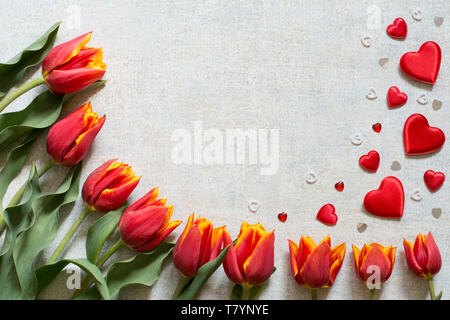 Border with red and yellow tulips and hearts on light background - text space, greeting card Stock Photo