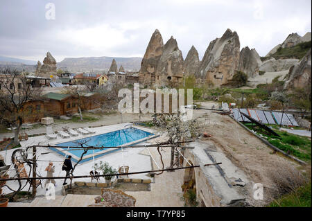 Guests walking near swiming pool at hotel with cabins in the town of Goreme in the Cappadocia region of Turkey. Stock Photo