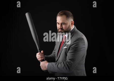 bearded Man in suit and red tie with baseball bat on black background Stock Photo