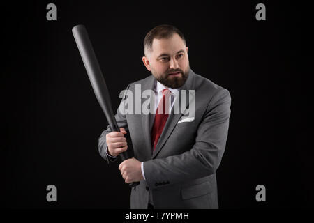 bearded Man in suit and red tie with baseball bat on black background Stock Photo