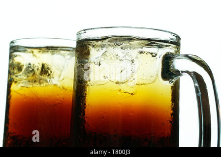 Close up two  pint glasses of cola with ice on bright background. Stock Photo