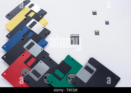 The evolution of digital data storage device. Floppy disks vs small memory cards. Isolated on a white background. Modern and retro technology. Stock Photo