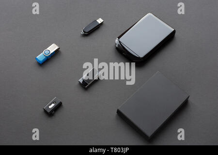 Modern digital devices for the transfer and storage of information. Flash drives and external hard disks. Objects isolated on dark background. Stock Photo