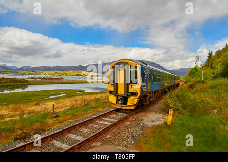 SCOTRAIL KYLE LINE INVERNESS TO KYLE OF LOCHALSH SCOTLAND TRAIN LEAVING ATTADALE STATION LOCH CARRON AND VILLAGE IN THE DISTANCE Stock Photo
