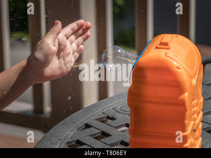 Childs mechanical soap bubble maker or blower with girls hand in front Stock Photo