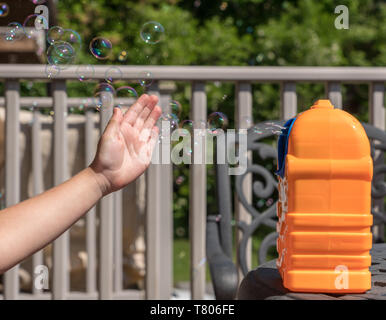 Childs mechanical soap bubble maker or blower with girls hand in front Stock Photo