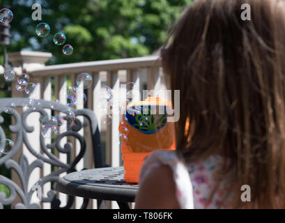 Childs mechanical soap bubble maker or blower with girl in front Stock Photo