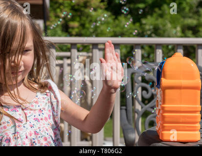 Childs mechanical soap bubble maker or blower with girl in front Stock Photo