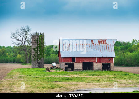 Old barn of wood and stone with rusty tin roof beside a silo in rural Kansas, USA. Stock Photo