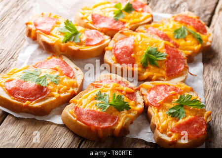 Homemade hot toasts with sausage and melted cheddar cheese close-up on the table. horizontal Stock Photo