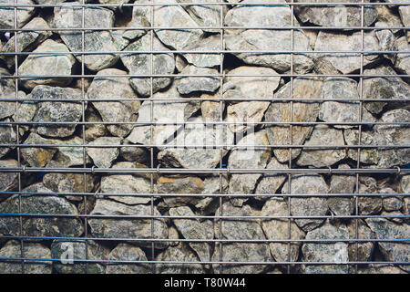 a metal grid behind which there is a large number of cobblestones and stones, closeup of decorations in the city or some kind of fortification Stock Photo